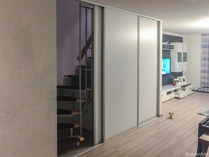 deckenhohe Schiebetüren als Raumteiler zwischen Wohnzimmer und Treppenaufgang